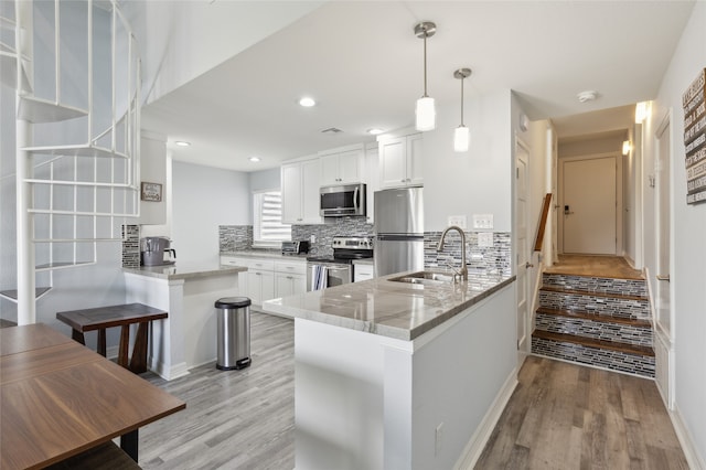 kitchen featuring light stone counters, sink, kitchen peninsula, and appliances with stainless steel finishes