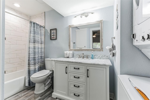 bathroom with toilet, stacked washer and dryer, wood finished floors, vanity, and shower / bath combo