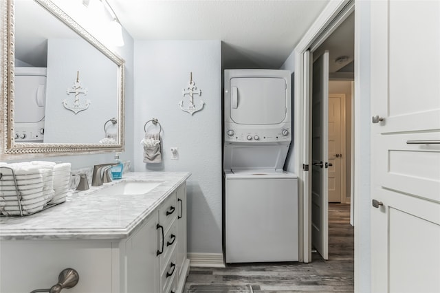 bathroom with a textured ceiling, stacked washer and clothes dryer, vanity, and wood-type flooring