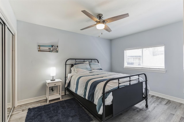 bedroom with ceiling fan, light wood finished floors, a closet, and baseboards