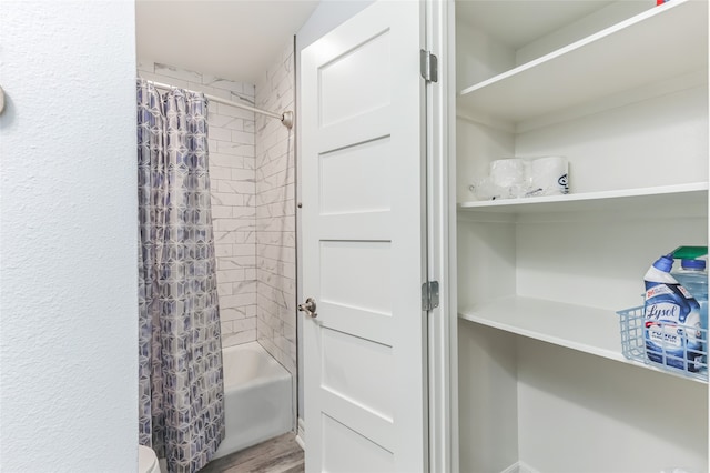 bathroom featuring hardwood / wood-style floors, shower / tub combo with curtain, and toilet