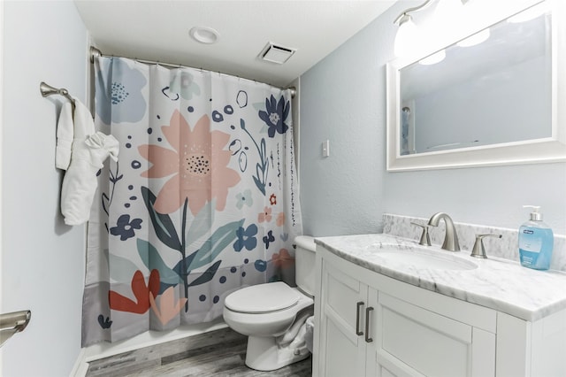 bathroom featuring visible vents, a shower with shower curtain, toilet, wood finished floors, and vanity