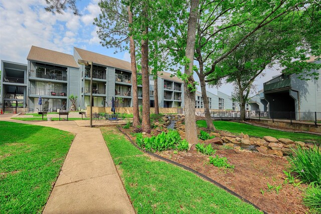 view of community featuring a lawn and fence