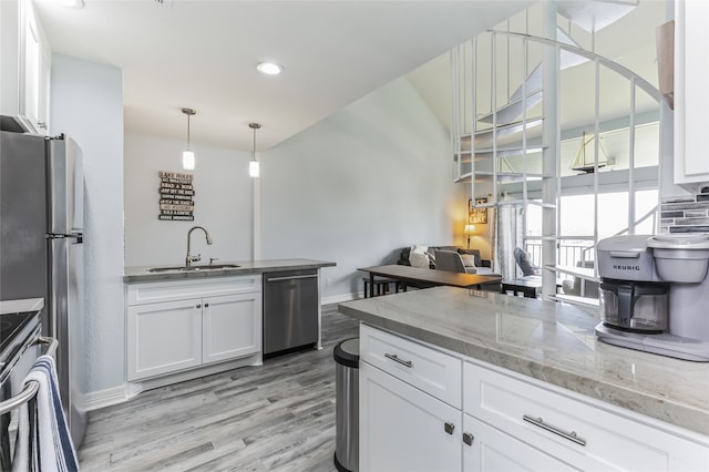 kitchen with light stone counters, stainless steel appliances, light wood-type flooring, white cabinets, and sink