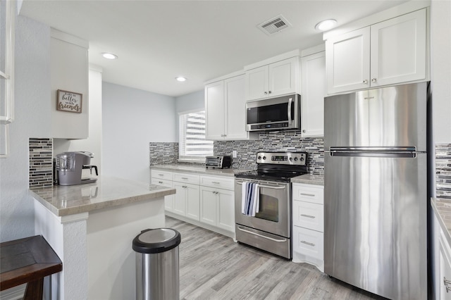 kitchen with visible vents, white cabinetry, appliances with stainless steel finishes, light wood-type flooring, and tasteful backsplash