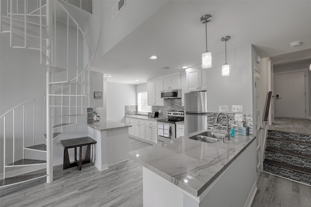 kitchen featuring light stone countertops, light hardwood / wood-style flooring, kitchen peninsula, and stainless steel appliances