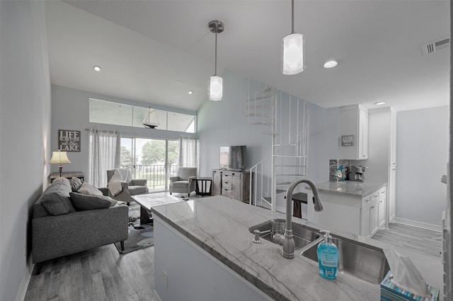 kitchen featuring a sink, white cabinetry, visible vents, light stone countertops, and light wood finished floors