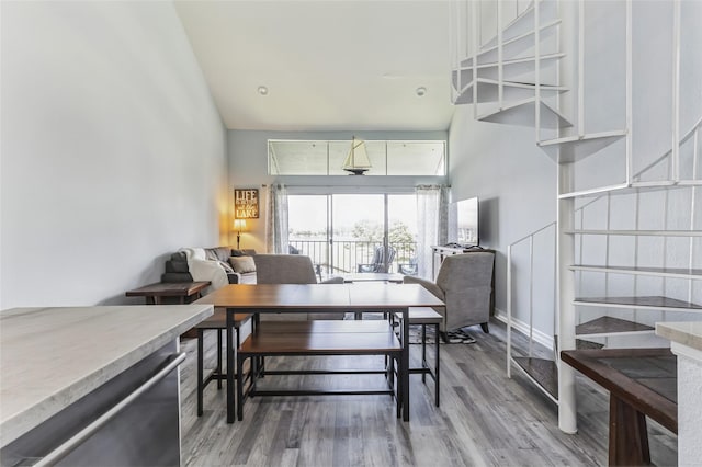 dining room with baseboards, light wood finished floors, and a high ceiling