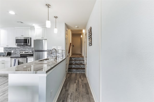 kitchen featuring white cabinetry, light stone countertops, appliances with stainless steel finishes, hardwood / wood-style flooring, and sink