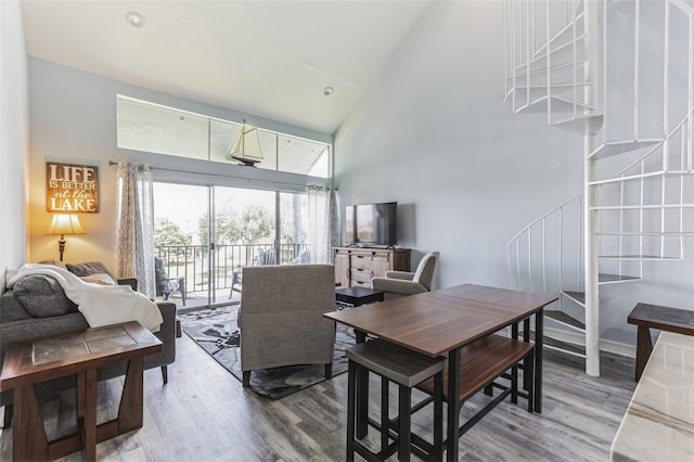 dining space featuring light wood-style floors, high vaulted ceiling, and stairs