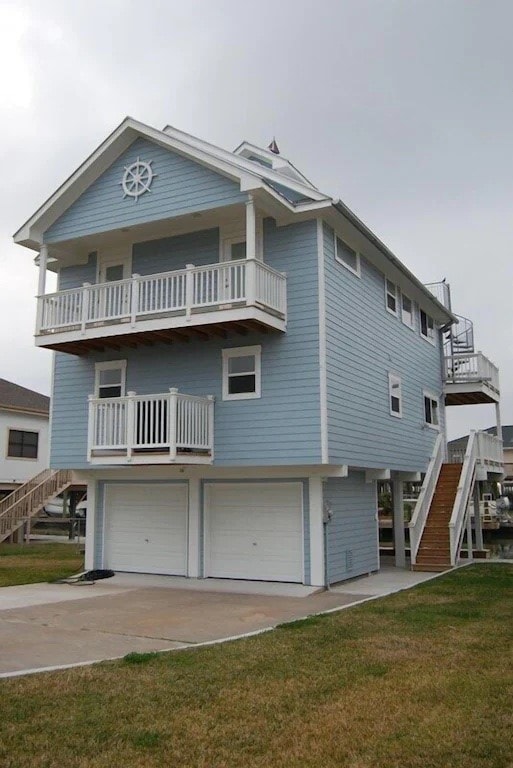 rear view of house with a garage, a balcony, and a lawn