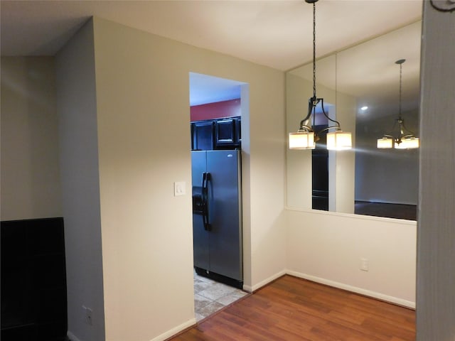 kitchen with hardwood / wood-style floors, stainless steel fridge, and decorative light fixtures