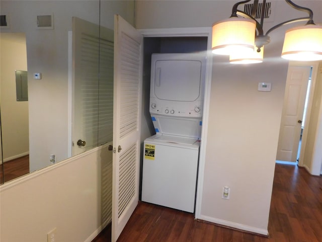 laundry area with dark wood-type flooring, electric panel, and stacked washing maching and dryer