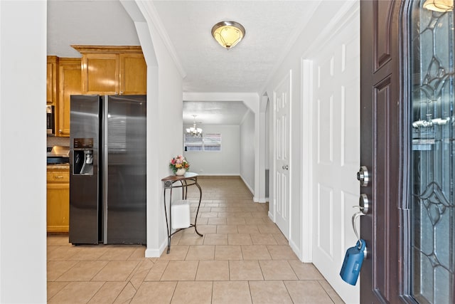 interior space featuring light tile patterned flooring, black refrigerator with ice dispenser, an inviting chandelier, and ornamental molding