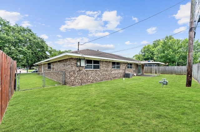 rear view of house with central AC unit and a yard