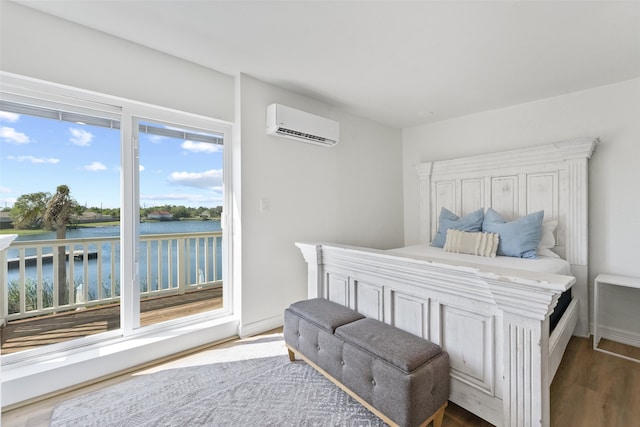 bedroom featuring an AC wall unit, a water view, and hardwood / wood-style flooring