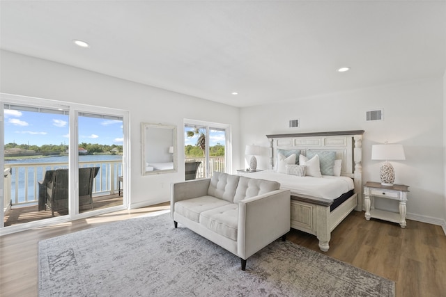 bedroom with a water view, hardwood / wood-style floors, and access to exterior