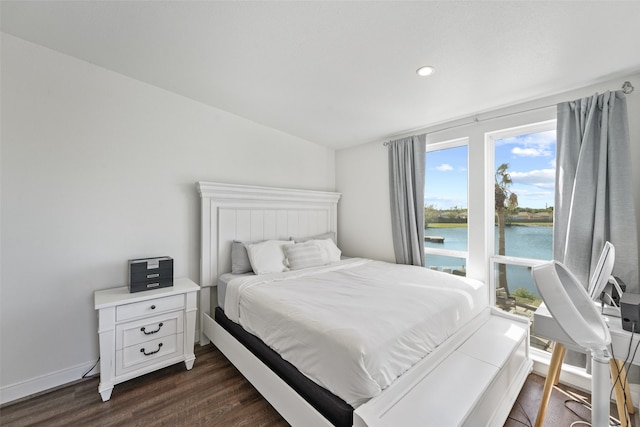 bedroom featuring dark hardwood / wood-style flooring and a water view