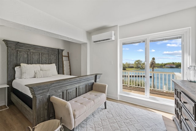 bedroom with multiple windows, a water view, and light hardwood / wood-style floors