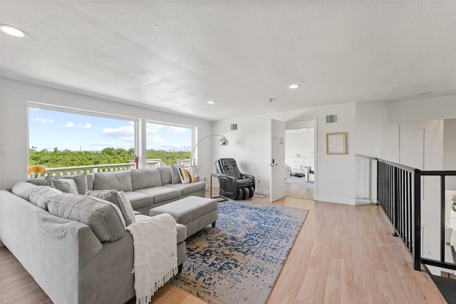 living room with light wood-type flooring and a textured ceiling