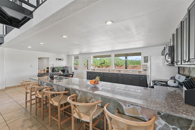 kitchen featuring stone counters, light tile patterned floors, range, white fridge, and sink