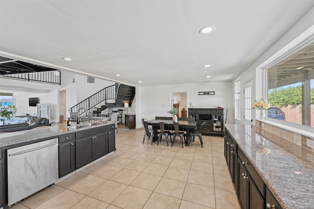 kitchen featuring sink, light tile patterned floors, stone countertops, and dishwasher