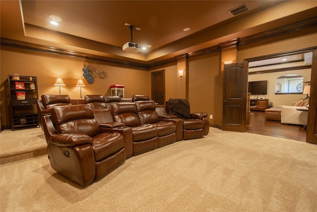 carpeted home theater room featuring a tray ceiling and ornamental molding