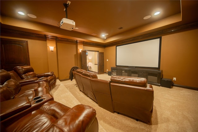 home theater room with a tray ceiling and light colored carpet