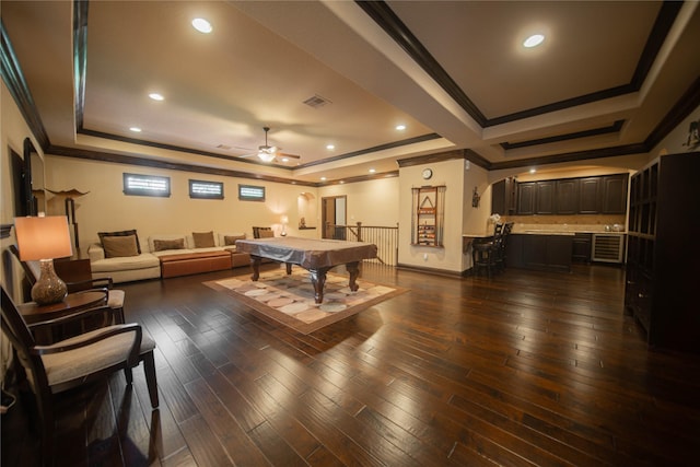 rec room with dark hardwood / wood-style floors, ceiling fan, ornamental molding, pool table, and a tray ceiling