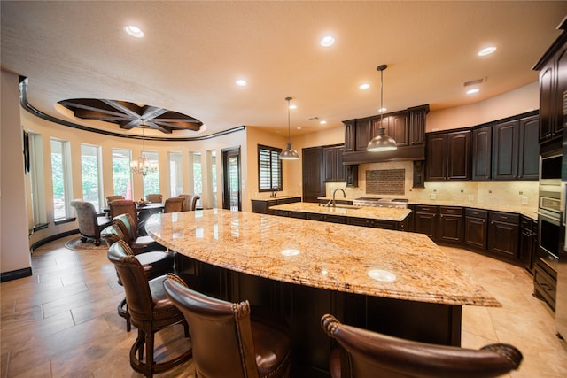 kitchen with decorative light fixtures, beam ceiling, dark brown cabinetry, and coffered ceiling