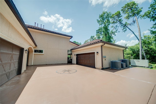 view of property exterior featuring a garage and central AC unit