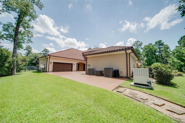 exterior space featuring a front yard, a garage, and central AC unit