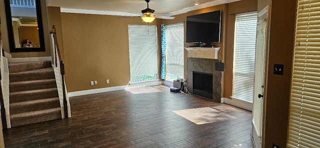 unfurnished living room featuring dark wood-type flooring, ceiling fan, a tile fireplace, and crown molding