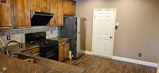 kitchen with extractor fan, dark wood-type flooring, black gas range, sink, and stainless steel refrigerator