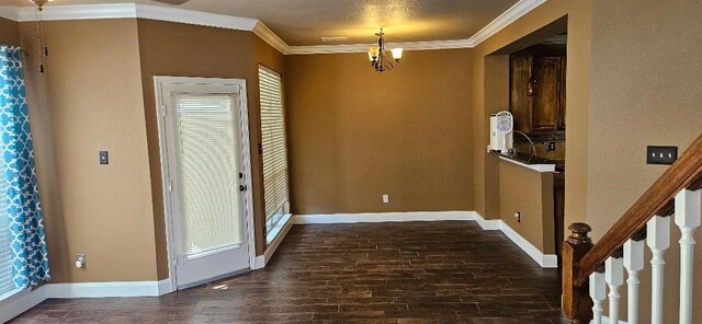 foyer entrance with ornamental molding, dark hardwood / wood-style flooring, a textured ceiling, and a chandelier