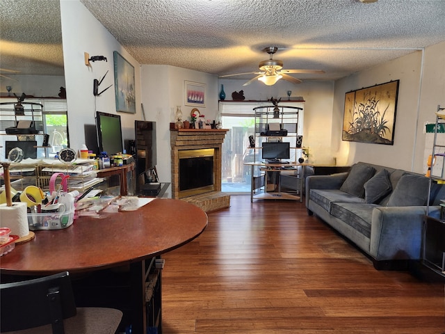 living room featuring a brick fireplace, dark hardwood / wood-style flooring, a textured ceiling, and plenty of natural light