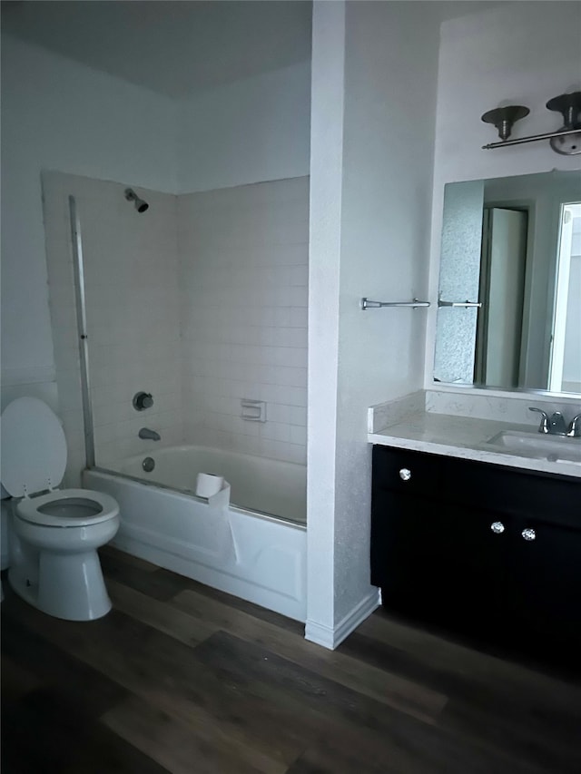 full bathroom with hardwood / wood-style floors, toilet, tiled shower / bath combo, and vanity