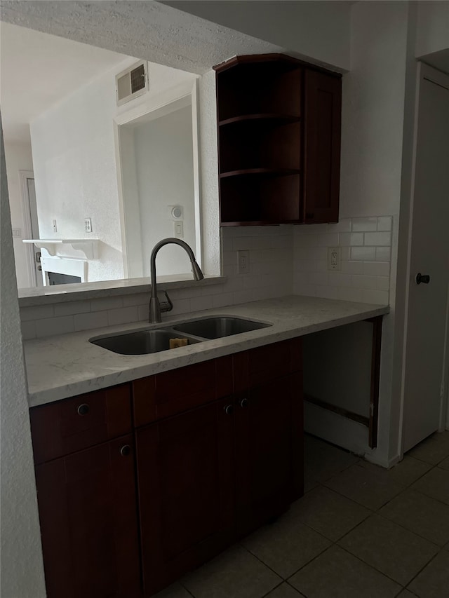 kitchen featuring light tile patterned floors, backsplash, sink, and light stone countertops