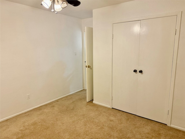 unfurnished bedroom with ceiling fan, light colored carpet, and a closet