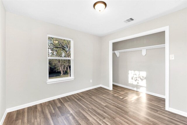 unfurnished bedroom with a closet, hardwood / wood-style floors, and multiple windows