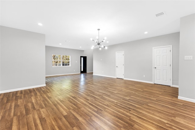 unfurnished living room featuring wood-type flooring and an inviting chandelier