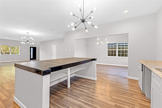 kitchen with pendant lighting, a notable chandelier, white cabinetry, and light hardwood / wood-style floors