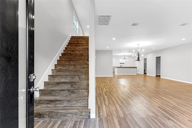 stairs with a notable chandelier and wood-type flooring