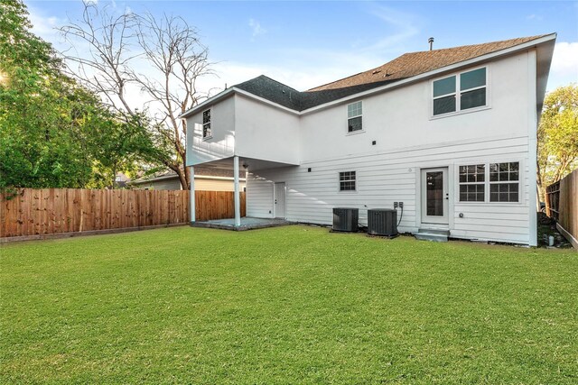 rear view of property with a yard and central AC unit