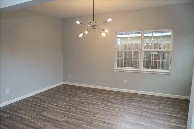 spare room with a notable chandelier and dark hardwood / wood-style flooring