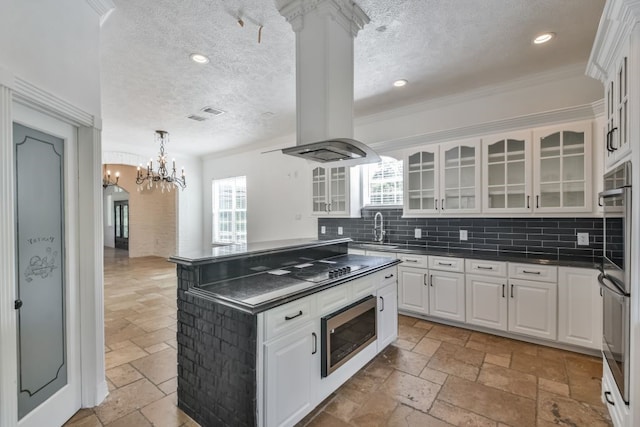 kitchen with light tile flooring, island range hood, tasteful backsplash, white cabinetry, and sink