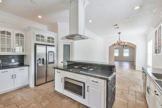 kitchen featuring crown molding, appliances with stainless steel finishes, white cabinets, extractor fan, and tasteful backsplash