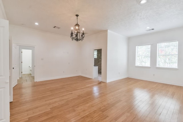 interior space with an inviting chandelier, ornamental molding, a textured ceiling, and light wood-type flooring