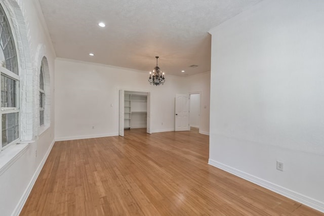 unfurnished room featuring light hardwood / wood-style flooring, a textured ceiling, and a chandelier