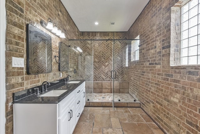 bathroom featuring brick wall, dual vanity, walk in shower, and tile flooring